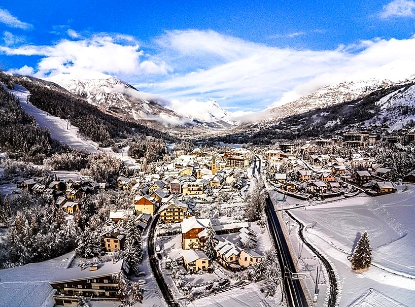 Chantemerle village under snow at dusk, lights on, mountains rising on both sides of the valley