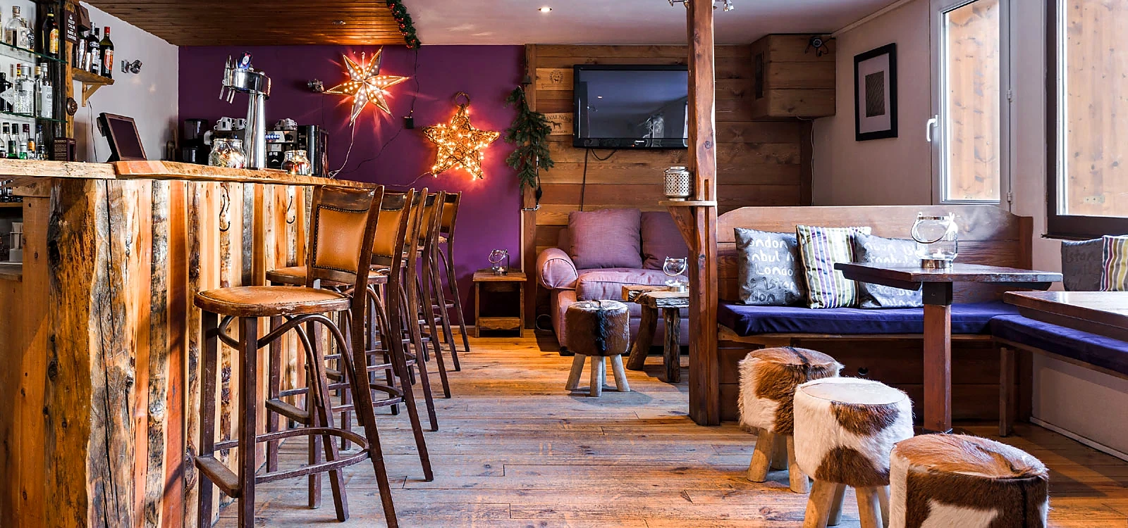 The bar at Hôtel Plein Sud: live-edge timber counter, leather stools and cowhide seats under star lights