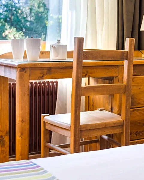 Timber desk and chair in a guest room, cups set out beside the window